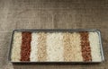 Ten different varieties of rice in a metal rectangular dish on the background of sacking. Royalty Free Stock Photo