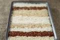 Ten different varieties of rice in rectangular dish on the background of sacking. Royalty Free Stock Photo