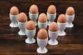 Ten eggs in egg cups on a wooden table. Shallow DOF