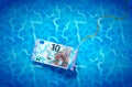 Ten euro banknote on glossy silver metal fishing hook in a blue shiny water, fraud concept