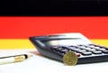 Ten Germany euro cent on obverse on white floor with black calculator and pencil, Germany flag background. Royalty Free Stock Photo