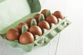 Ten large brown chicken eggs in green carton package on white wooden table Royalty Free Stock Photo