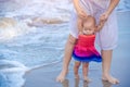 Ten months baby girl on the beach first time with mother. Infant feeling worry and excited playing on the beach. Mother hold