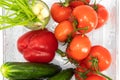 Ten red tomatoes on a branch, one red bell pepper, four large cucumbers, green onions in a glass, top view Royalty Free Stock Photo