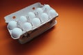 Ten white eggs in a carton package. Cardboard egg box on orange background Royalty Free Stock Photo