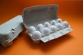 Ten white eggs in a carton package. Cardboard egg box on orange background Royalty Free Stock Photo