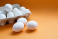 Ten white eggs in a carton package. Cardboard egg box on orange background Royalty Free Stock Photo