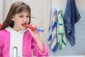 Ten year old girl brushes her teeth with an electric toothbrush in the bathroom