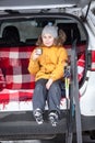 Ten years child sits in trunk of car, drinks hot tea after skiing in wintry woods Royalty Free Stock Photo