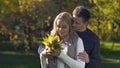 Tender boyfriend presenting bouquet of autumn leaves to girlfriend, having fun