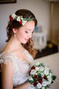 Tender bride in light dress and red wreathe over her curly hair