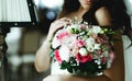 Tender bride touches a pink wedding bouquet standing in the hotel