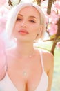 Tender close-up portrait of a beautiful woman between cherry blossom branches under the rays of the sun Royalty Free Stock Photo