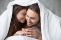 Tender couple relaxing under blanket on Sunday morning in bed Royalty Free Stock Photo