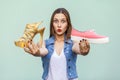 The tender and cute teenage girl with freckles got choosing sneakers or high heels, looking at camera with wonder face. Royalty Free Stock Photo