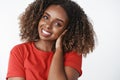 Tender friendly-looking attractive young african-american woman with curly afro hairstyle combing hair with hand gently