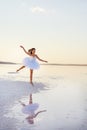 Tender girl ballerina in a white ballet dress in a graceful jump on the lake. Royalty Free Stock Photo