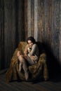 Tender girl in warm knee socks and sweater with Teddy bear in her hands sitting in armchair in wooden room Royalty Free Stock Photo