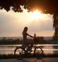 Tender girl rides a retro bike with basket on road near the river on sunset Royalty Free Stock Photo