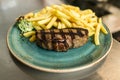 Tender grilled porterhouse steak served with crisp golden French fries and fresh green herb salad by BBQ or herb butter Royalty Free Stock Photo