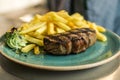 Tender grilled porterhouse steak served with crisp golden French fries and fresh green herb salad by BBQ or herb butter Royalty Free Stock Photo