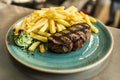 Tender grilled porterhouse steak served with crisp golden French fries and fresh green herb salad by BBQ or herb butter Royalty Free Stock Photo