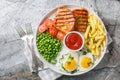 Tender grilled steak served with crisp golden French fries, fied eggs, green pea and fresh tomato closeup on the plate. Horizontal Royalty Free Stock Photo