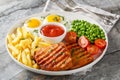 Tender grilled steak served with crisp golden French fries, fied eggs, green pea and fresh tomato closeup on the plate. Horizontal Royalty Free Stock Photo