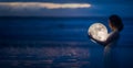 Tender image of a girl. Female magic. Beautiful attractive girl on a night beach with sand hugs the moon, art photo. On a dark Royalty Free Stock Photo