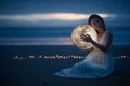 Tender image of a girl; female magic. Beautiful attractive girl on a night beach with sand and stars hugs the moon, art photo. On Royalty Free Stock Photo