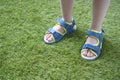 Tender kid legs in sandals close-up on the soft artificial grass Royalty Free Stock Photo