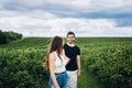A tender loving couple walking in a field of currant. A smiling woman with long hair leads a man, holding his hand Royalty Free Stock Photo