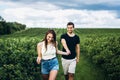 A tender loving couple walking in a field of currant. A smiling woman with long hair leads a man, holding his hand Royalty Free Stock Photo