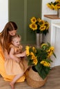 Tender mother and daughter happy together, hugging and having fun in the room full of sunflowers Royalty Free Stock Photo