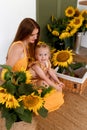 Tender mother and daughter happy together, hugging and having fun in the room full of sunflowers Royalty Free Stock Photo