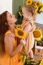 Tender mother and daughter happy together, hugging and having fun in the room full of sunflowers Royalty Free Stock Photo