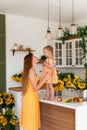 Tender mother and daughter happy together, hugging and having fun in the room full of sunflowers Royalty Free Stock Photo