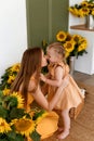 Tender mother and daughter happy together, hugging and having fun in the room full of sunflowers Royalty Free Stock Photo