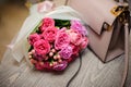 Tender pink flowers near the stylish handbag on the table Royalty Free Stock Photo