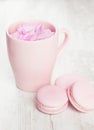 Tender pink macaroons and tea cup on white wood background Royalty Free Stock Photo