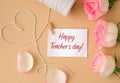 Tender pink roses with spool of white cotton rope in heart shape on beige background. Paper note with text HAPPY