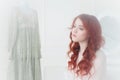 Tender portrait of a young dreamy redhead woman in nightdress. She is sitting in dress room and planning to wear beautiful vintage Royalty Free Stock Photo