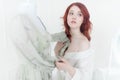 Tender portrait of a young dreamy redhead woman in nightdress. She is standing in dress room and planning to wear beautiful vintag Royalty Free Stock Photo