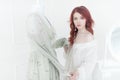 Tender portrait of a young dreamy redhead woman in nightdress. She is standing in dress room and planning to wear beautiful vintag Royalty Free Stock Photo