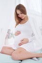 Tender pregnant woman touching belly sitting on the windowsill i