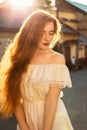Tender red haired woman with naked shoulders posing in sun glare