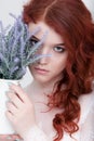 Tender retro portrait of a young beautiful dreamy redhead woman in beautiful white dress with bouquet of lavender. Royalty Free Stock Photo