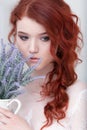 Tender retro portrait of a young beautiful dreamy redhead woman in beautiful white dress with bouquet of lavender. Royalty Free Stock Photo