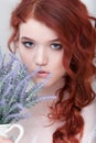 Tender retro portrait of a young beautiful dreamy redhead woman in beautiful white dress with bouquet of lavender.