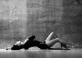 Tender sensual woman in little black dress is lying sexual posing on the floor touching her neck Royalty Free Stock Photo